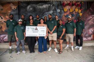Rep. Rashida Tlaib standing with a group of After the Storm team members holding a large check for $1 million